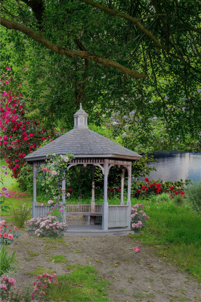 White gazebo surrounded by roses beside a lake
